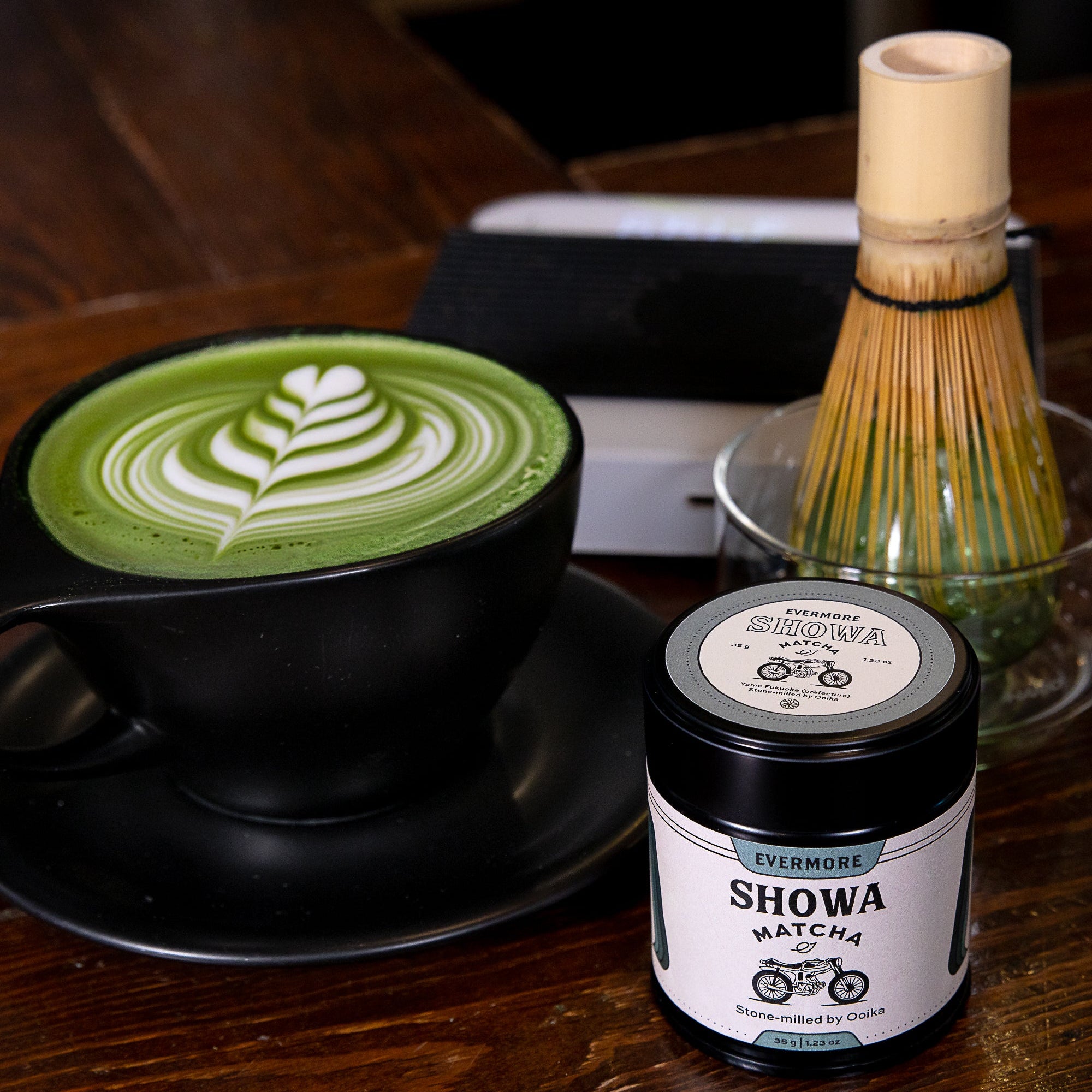 Cup of matcha latte with a container of Showa Matcha on a wooden table.